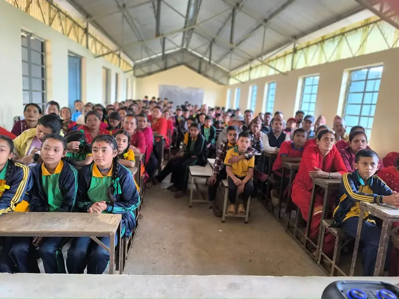 Students, parents, and teachers seated together in a classroom for a school community meeting