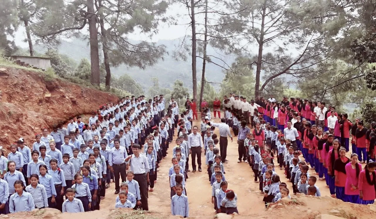 Students and teachers lined up for morning assembly on a hillside outside their school