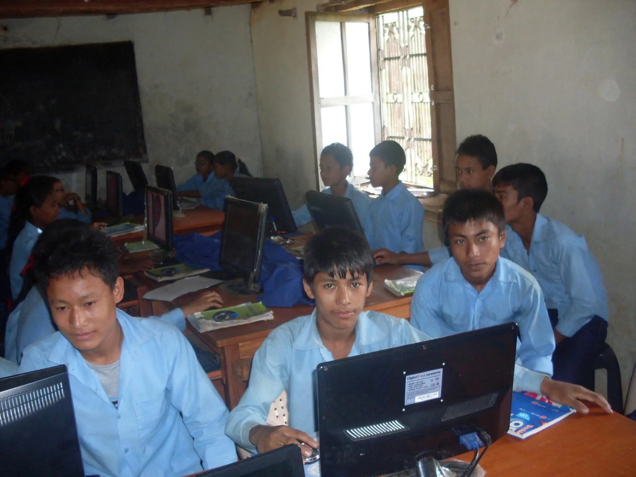 Nepali students using laptops together in a rural classroom